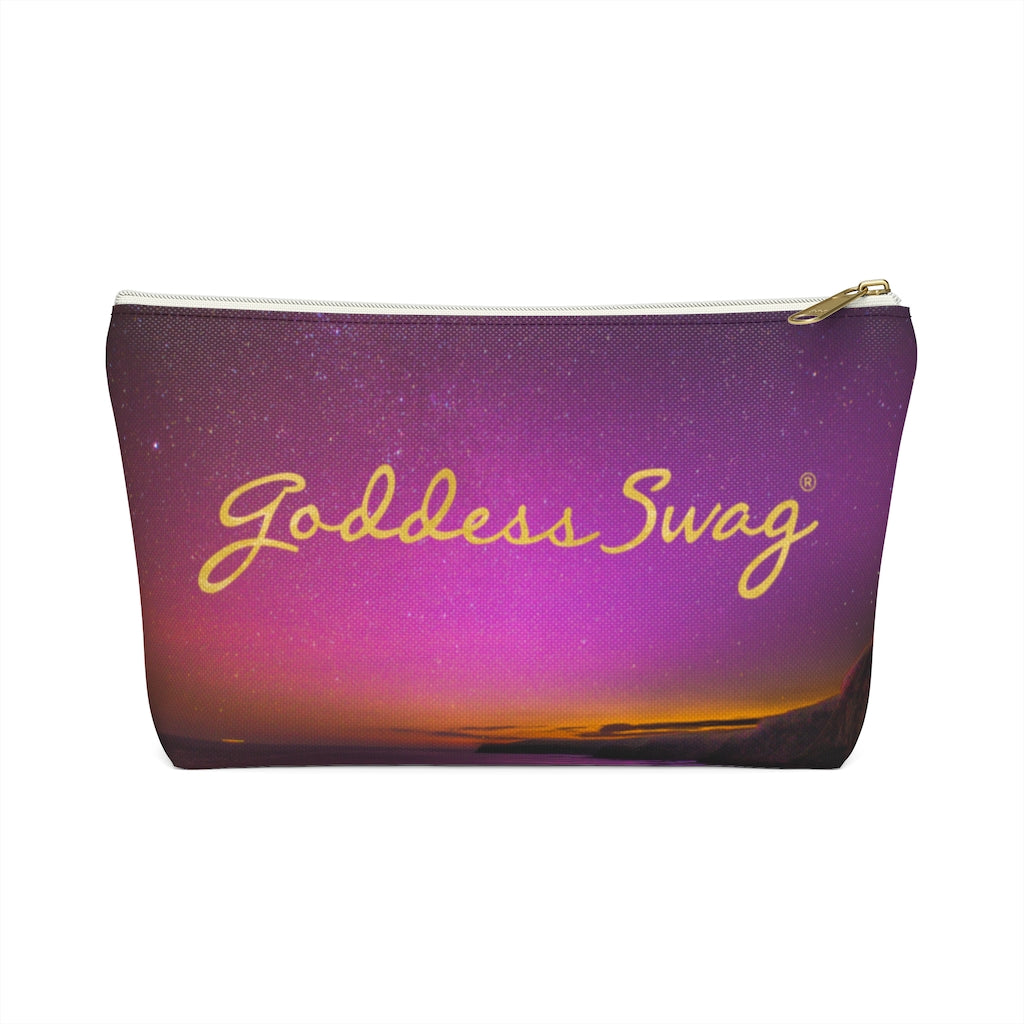 Goddess Swag Bag Mini (named cosmic).  Item can be used as accessory pouch, makeup bag or cosmetic bag with a background is purple with some orange like sunset.  Goddess Swag wording is in gold on one side of the bag only.  There is an option of a black or a white zipper, and a large or a small bag. 