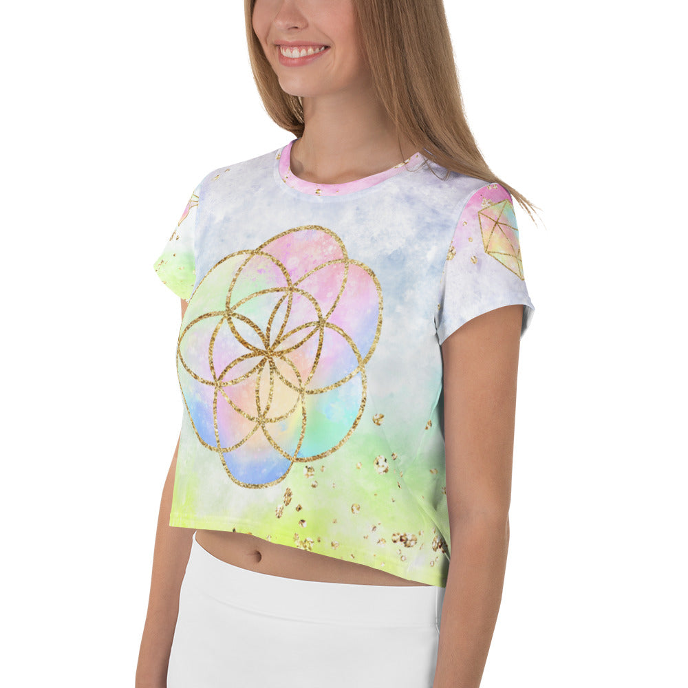 short sleeve crop top tee shirt pastel tie dye background with seed of life design in gold  on front.  Left sleeve has a hexagon and right has a star tetrahedron symbol.