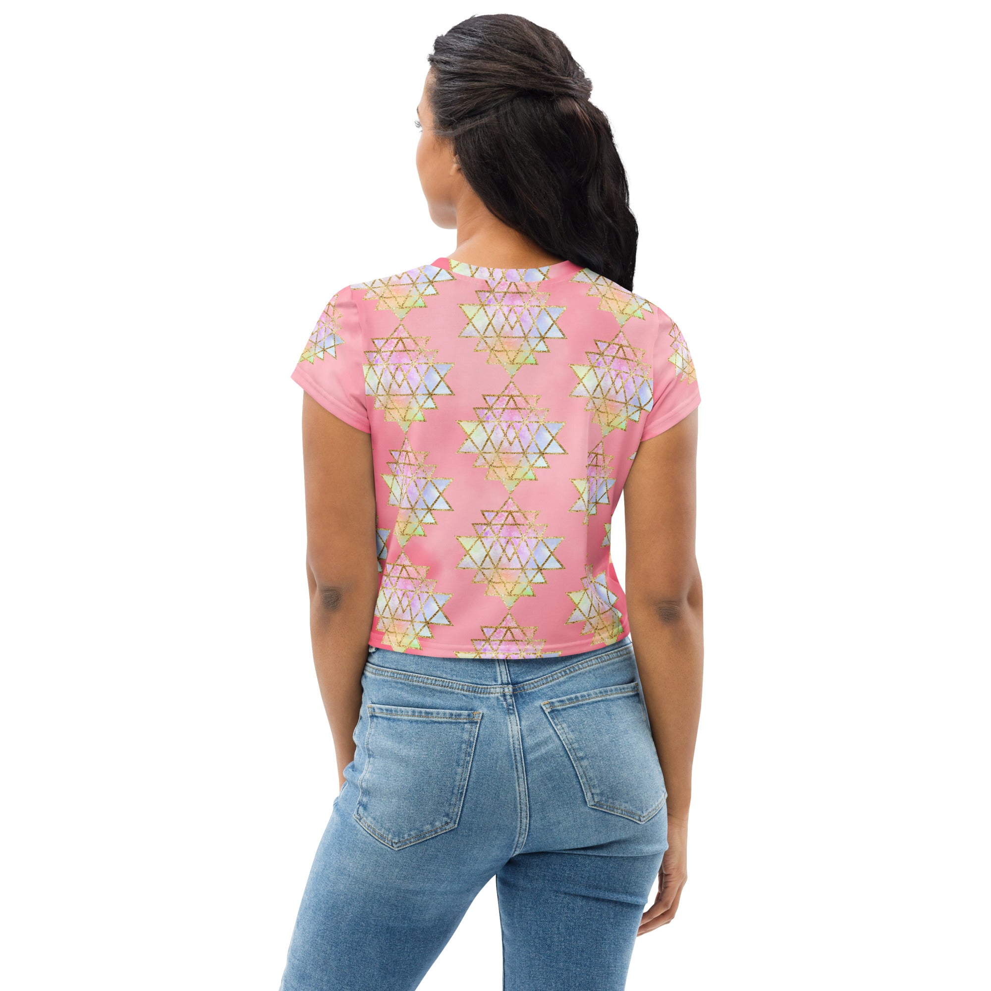 Light to medium pink background with pastel and gold color sri yantra design all over front back and short sleeves.  This is a crop top tee by goddess swag as part of the cosmic powers collection