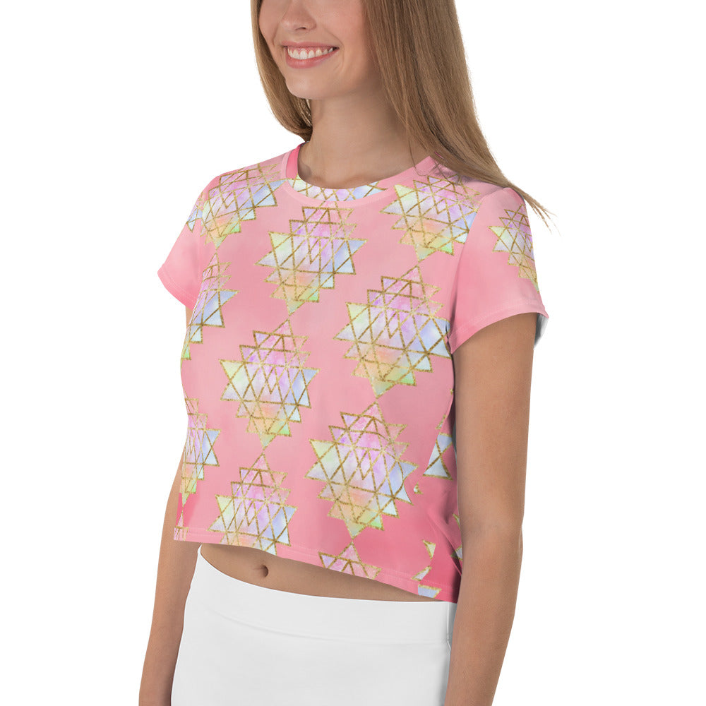 Light to medium pink background with pastel and gold color sri yantra design all over front back and short sleeves.  This is a crop top tee by goddess swag as part of the cosmic powers collection