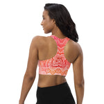 Load image into Gallery viewer, longline sports bra by goddess swag. the design has a pink orange background with an overlay of a root chakra mandala design in red and orange. this design is on front and back of sports bra.
