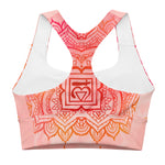 Load image into Gallery viewer, longline sports bra by goddess swag. the design has a pink orange background with an overlay of a root chakra mandala design in red and orange. this design is on front and back of sports bra.
