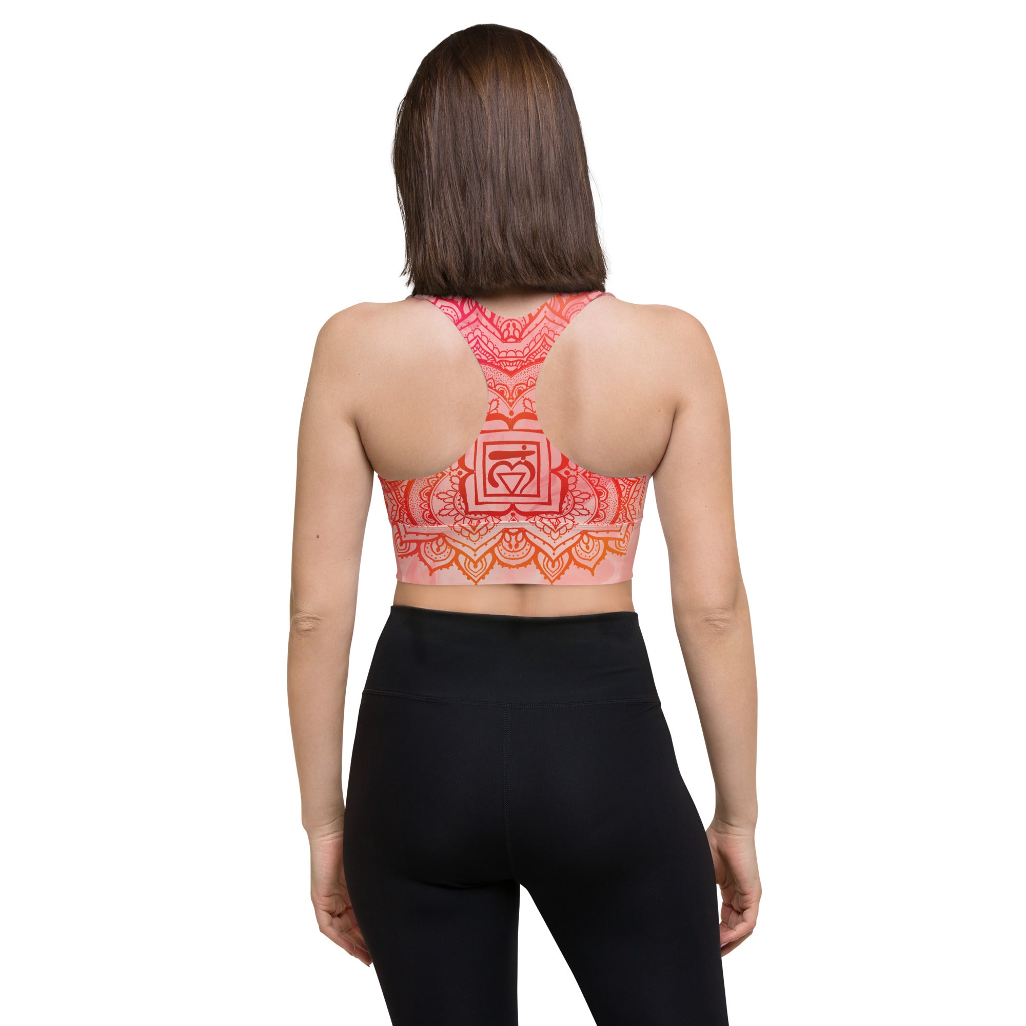 longline sports bra by goddess swag. the design has a pink orange background with an overlay of a root chakra mandala design in red and orange. this design is on front and back of sports bra.