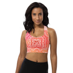 Load image into Gallery viewer, longline sports bra by goddess swag. the design has a pink orange background with an overlay of a root chakra mandala design in red and orange. this design is on front and back of sports bra.
