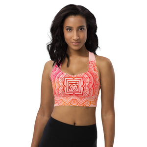 longline sports bra by goddess swag. the design has a pink orange background with an overlay of a root chakra mandala design in red and orange. this design is on front and back of sports bra.