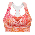 Load image into Gallery viewer, longline sports bra by goddess swag. the design has a pink orange background with an overlay of a root chakra mandala design in red and orange. this design is on front and back of sports bra.
