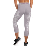 Load image into Gallery viewer, mystic-77-heart-chakra-mandala-capri-leggings-by-goddess-swag.  Background color is a light to medium mauve.  The mandala design is white and all over front and back. Goddess Swag is written on the back waistband in sanskrit style in a deep purple.
