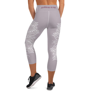 mystic-77-heart-chakra-mandala-capri-leggings-by-goddess-swag.  Background color is a light to medium mauve.  The mandala design is white and all over front and back. Goddess Swag is written on the back waistband in sanskrit style in a deep purple.