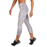Load image into Gallery viewer, mystic-77-heart-chakra-mandala-capri-leggings-by-goddess-swag.  Background color is a light to medium mauve.  The mandala design is white and all over front and back. Goddess Swag is written on the back waistband in sanskrit style in a deep purple.
