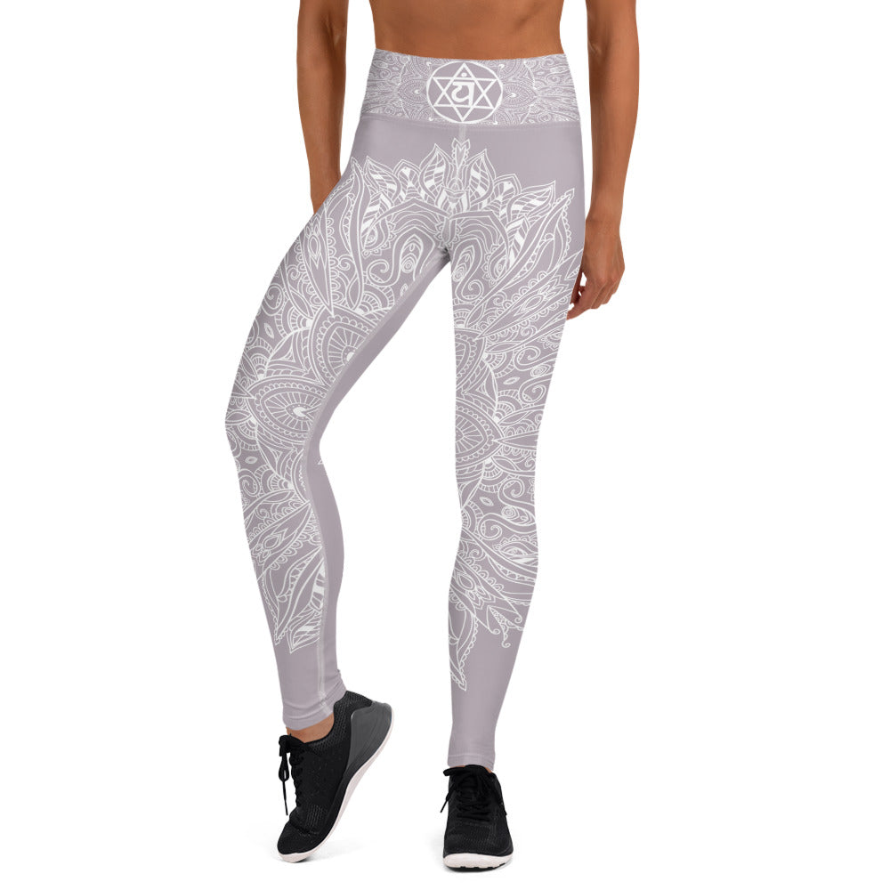 full length yoga legging from collection mystic mandala by goddess swag.  the design is a heart chakra symbol and mandala blown out on the front and back in white.  The front waistband has the 6 pointed star chakra design and the back waistband has goddess swag written. The background color os a solid light mauve gray.