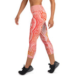 Load image into Gallery viewer, capri mid calf leggings. design is root chakra mandala of orange and red on legs front and back.  the front waistband has the root chakra symbol in the center while the back has goddess swag written on the waist band.
