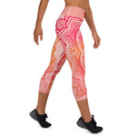 Load image into Gallery viewer, capri mid calf leggings. design is root chakra mandala of orange and red on legs front and back.  the front waistband has the root chakra symbol in the center while the back has goddess swag written on the waist band.
