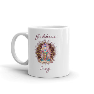 Goddess Swag, ceramic coffee mug 11 ounces. Goddess with Mandala behind her and seven colorful chakras from root to crown. She is sitting in lotus position. Goddess Swag which is written in deep purple color.